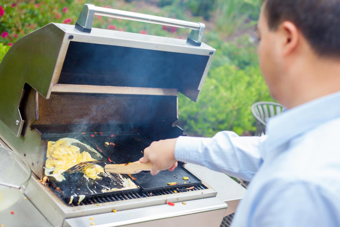 Vic frying eggs on a barbecue grill